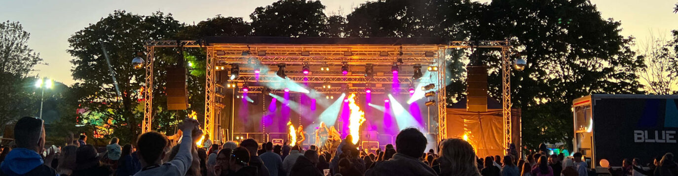 Evening crowd watching the main stage performance with lights and fire effects at the Cornwall Tribute Festival at Monkey Tree Holiday Park.