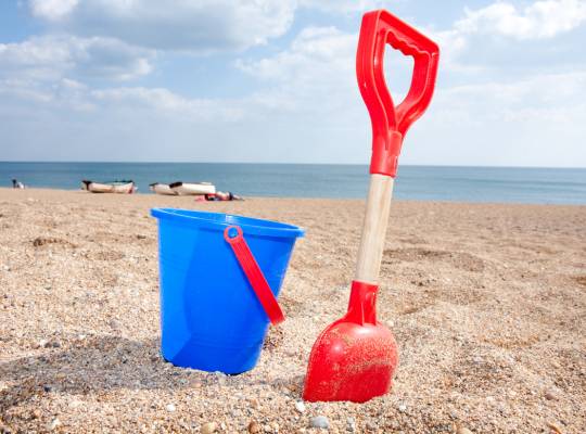 A bucket and spade on sand with the sea in the distance