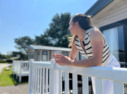 Guest enjoying a drink overlooking their Holiday Home decking at Monkey Tree Holiday Park