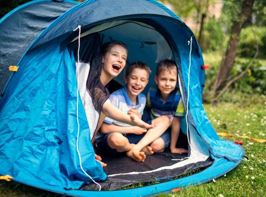 Happy Family inside a tent in Cornwall looking out
