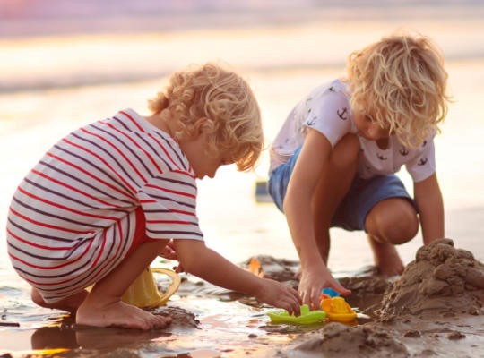 Boys playing on the beach at sunset at Tolcarne Beach, Newquay
