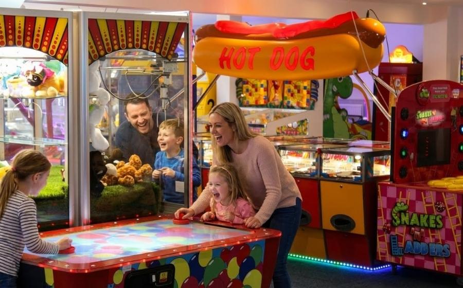 A family laugh and play on the arcade machines at monkey tree holiday park