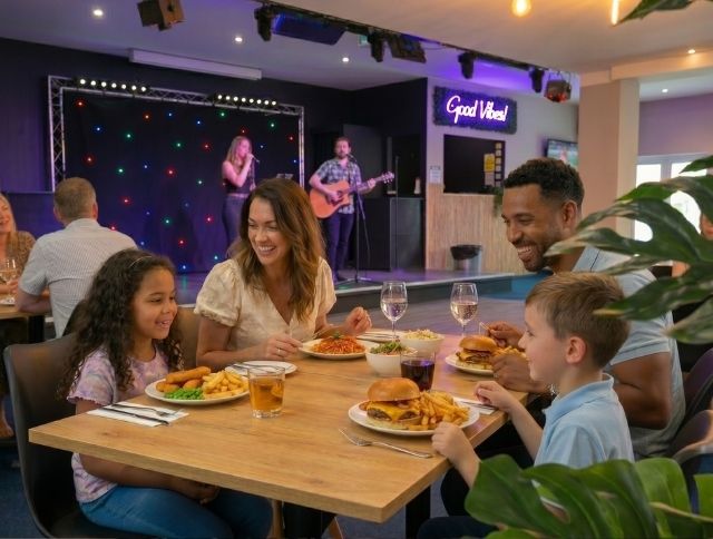 Guests dining and socialising inside The Beach Club at Monkey Tree Holiday Park, with modern decor, wooden tables, and ambient lighting.